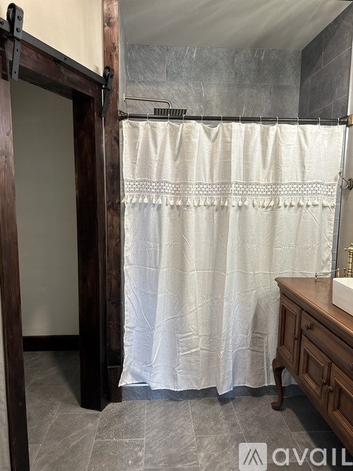 A bathroom with a white shower curtain and a wooden door.