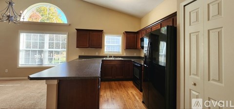 A kitchen with a black counter top and wooden cabinets.