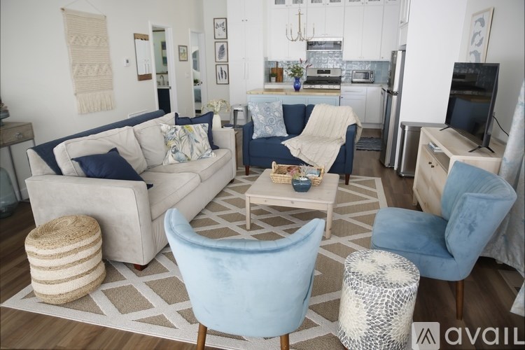 A living room with a white couch, blue chairs, and a rug.