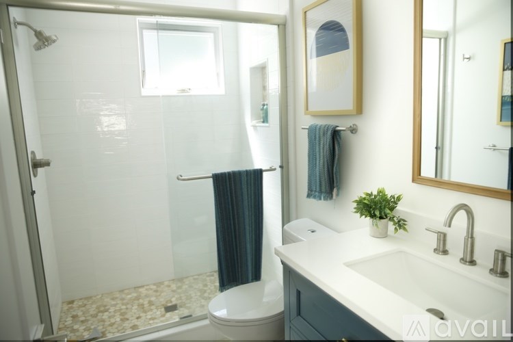A bathroom with a sink, mirror, and shower.