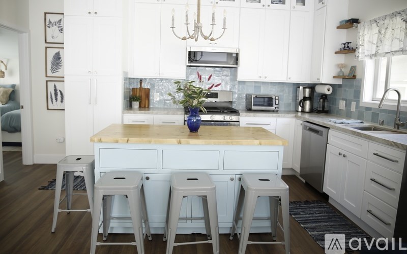 A kitchen with white cabinets and a wooden island with a vase of flowers on it.