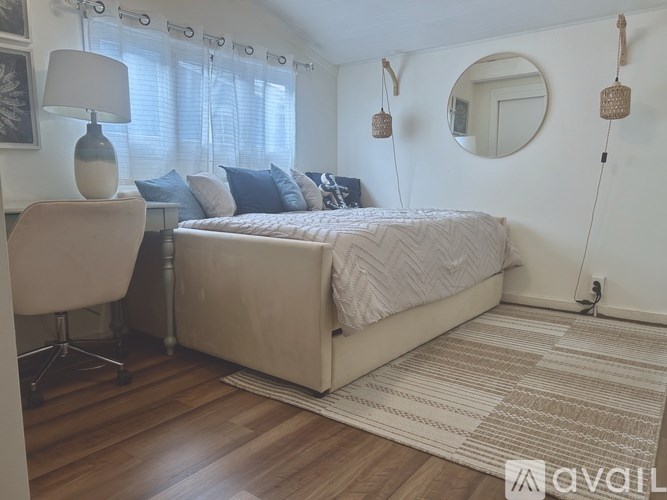 A bedroom with a bed, chair, and a rug.