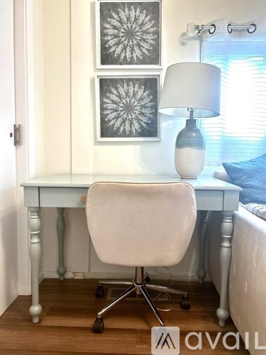A white desk with a white chair and a white lamp with a blue shade.