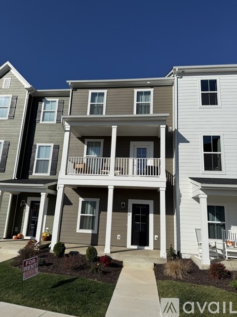 A row of townhouses with a for rent sign in front of the first one.