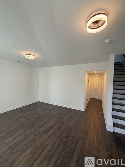 A room with wooden floors and a staircase leading to another room.
