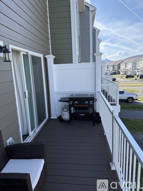 A patio with a white railing and a wicker chair.