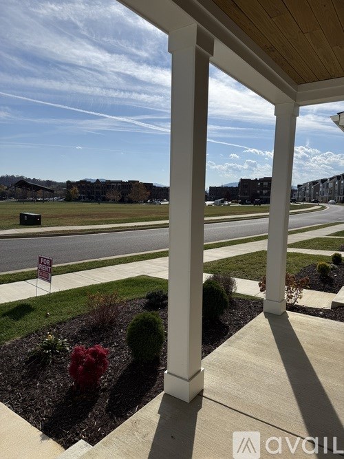 A view from a porch looking out at a street with a sign that says "For Sale".
