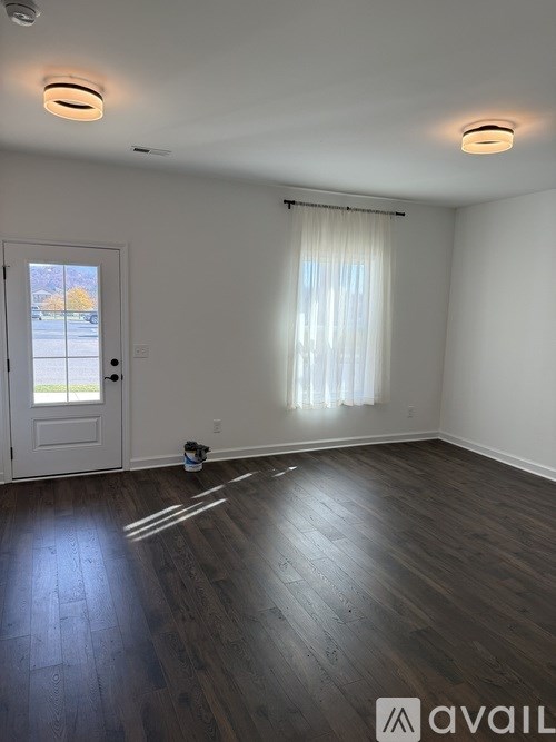 A room with a white door and a window with white curtains.