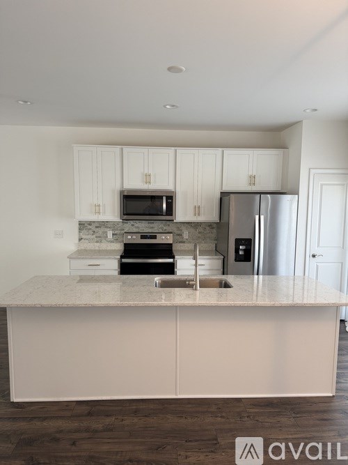 A kitchen with white cabinets and a marble countertop.