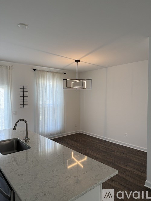 A kitchen with a marble countertop and a modern pendant light.