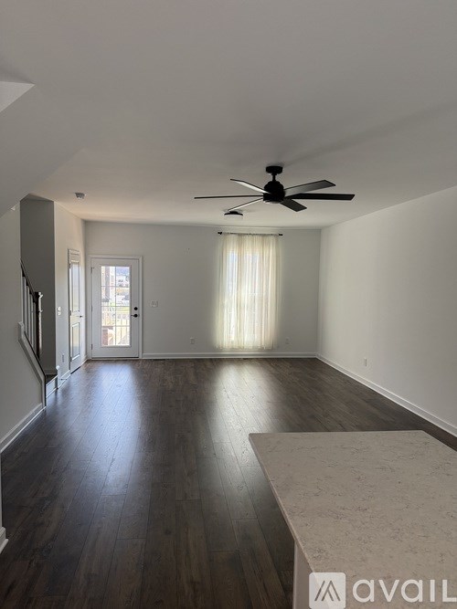 A spacious room with a ceiling fan and wooden flooring.