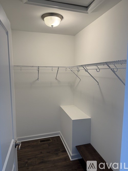 A white closet with a bench and a light on the ceiling.