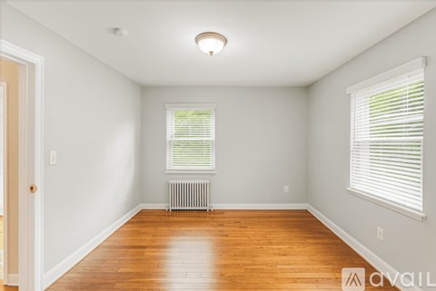 A room with wooden floors and a window with blinds.