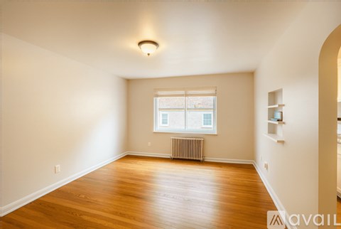 A spacious room with wooden floors and a window with a view of a snowy landscape outside.