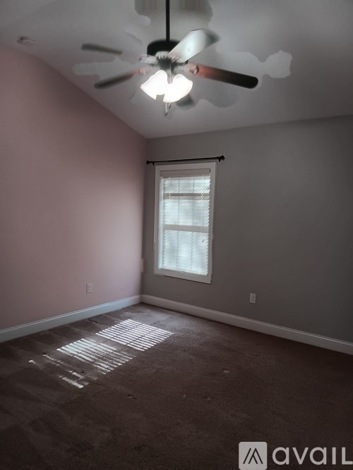 A room with a ceiling fan and a window.