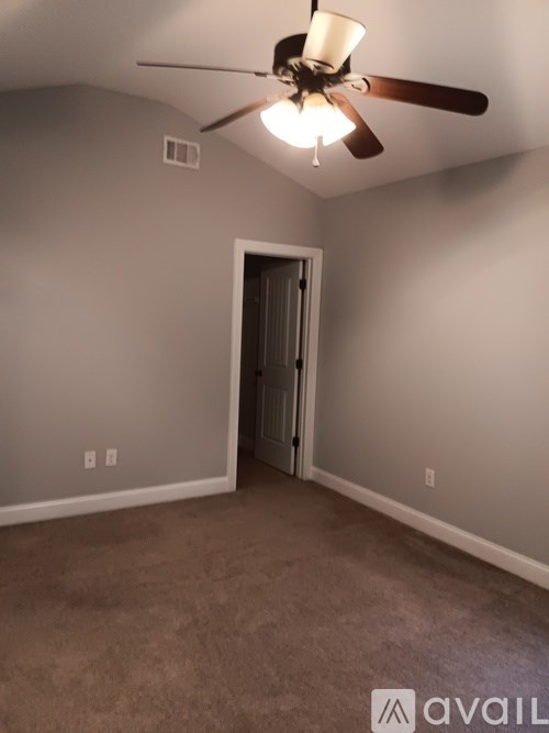 A room with a ceiling fan and carpeted floor.