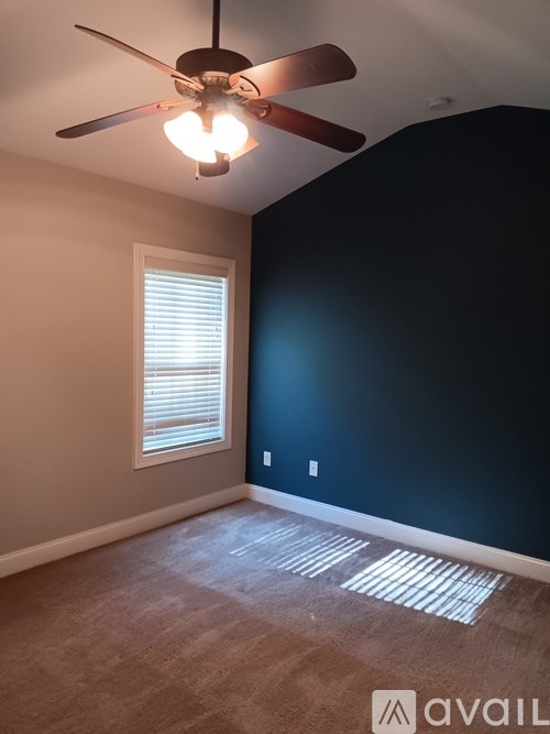A room with a ceiling fan and a window with blinds.