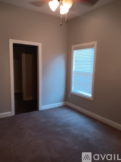 A room with a ceiling fan and a window with blinds.