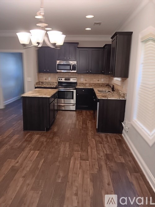 A kitchen with dark wood floors and black appliances.