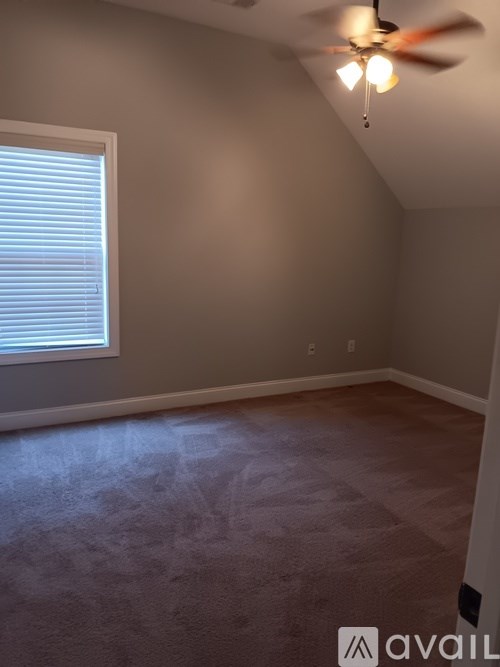 A room with a ceiling fan and a window with blinds.