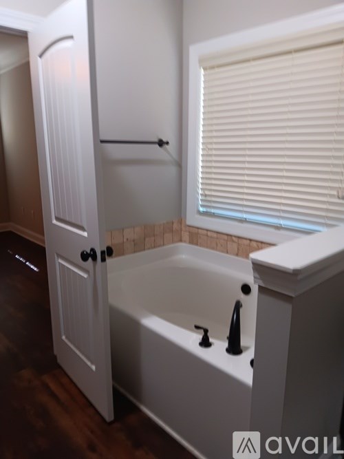 A white bathroom with a tub and a door.