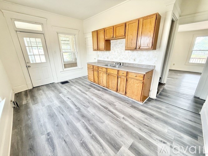 A kitchen with wooden cabinets and a grey floor.