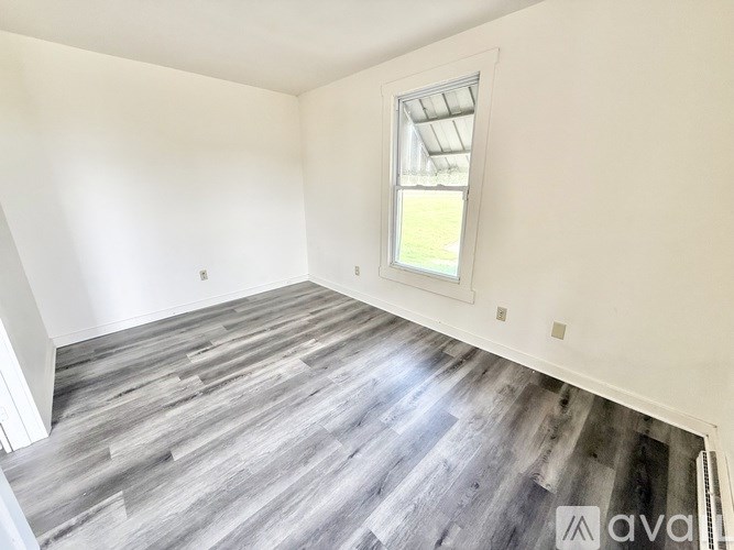 A room with a window and wooden flooring.