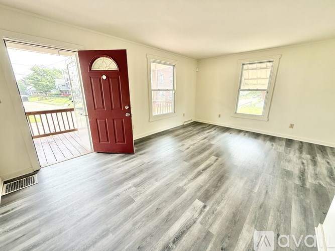 A room with a red door and grey flooring.