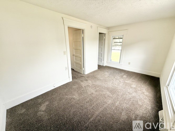 A room with a carpeted floor and a window with blinds.