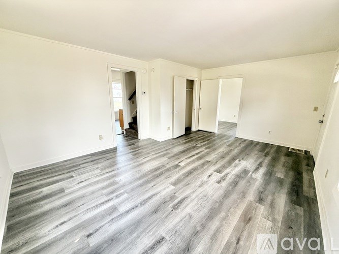 A spacious room with wood flooring and white walls.