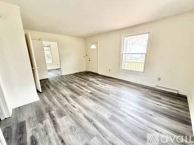 A room with a grey wooden floor and white walls.