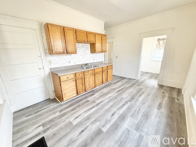 A kitchen with wooden cabinets and a grey floor.