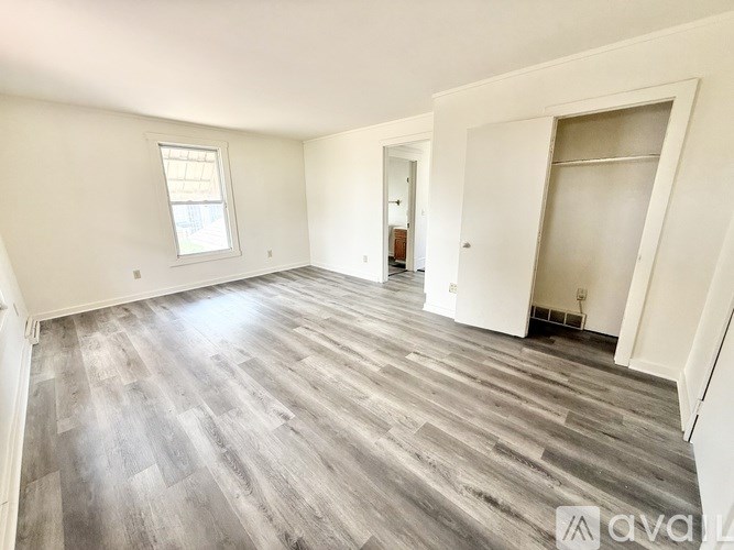 A spacious room with wooden flooring and white walls.