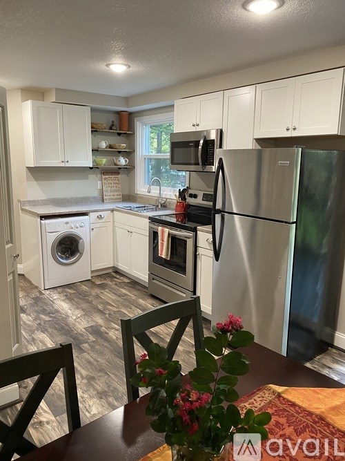 A kitchen with a refrigerator, washing machine, and microwave.