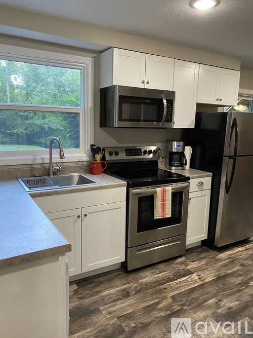 A kitchen with white cabinets and a black refrigerator.