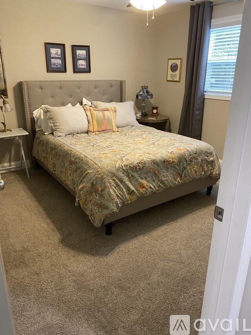 A bedroom with a bed, nightstand, and two pictures on the wall.