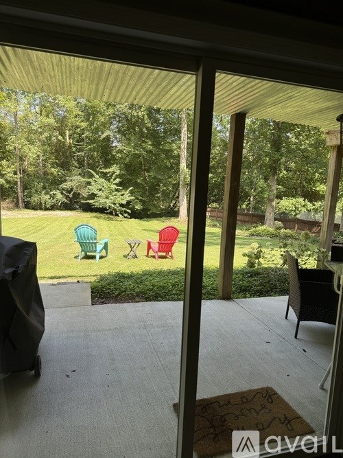 A patio with a table and chairs overlooking a green lawn.