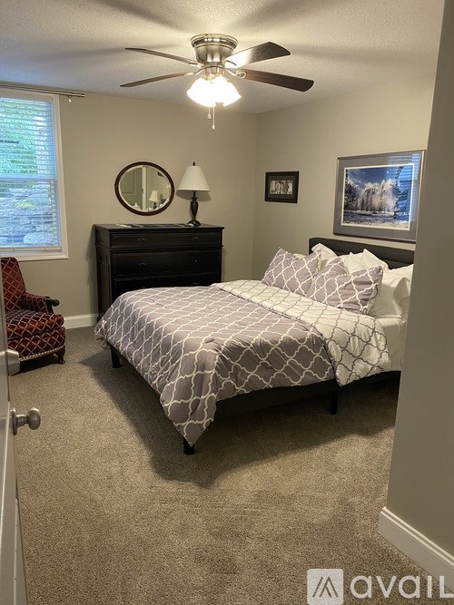 A bedroom with a bed, dresser, and chair.
