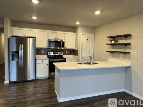 A modern kitchen with a refrigerator, microwave, oven, and sink.