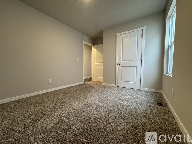A room with a carpeted floor and two doors.