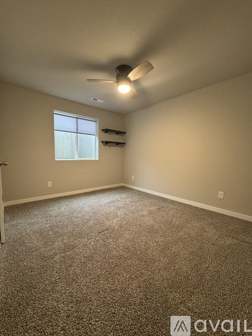A room with a carpeted floor, a ceiling fan, and a window.