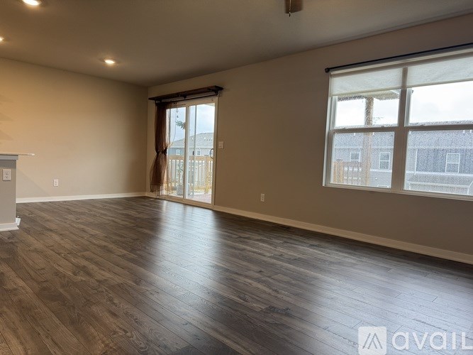 A spacious room with wooden flooring and a large window.