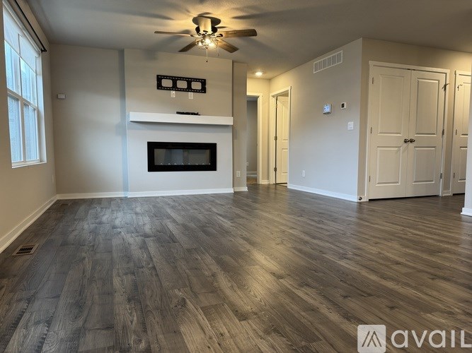 A spacious room with wood flooring and a ceiling fan.