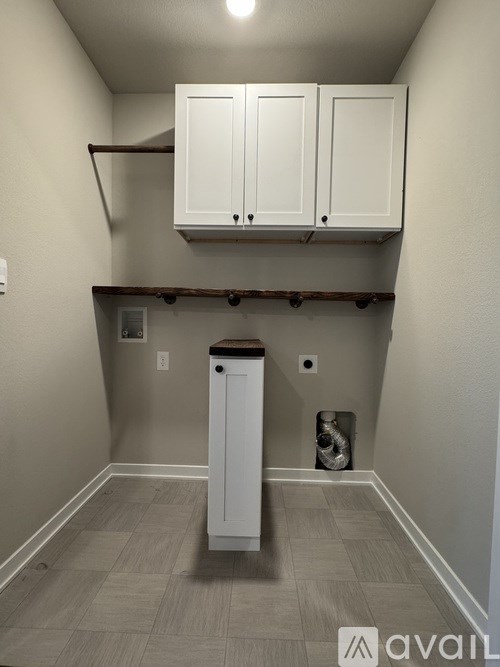 A small white cabinet is in a corner of a room.