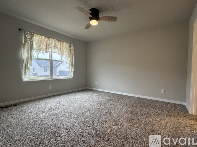 A room with a carpeted floor and a ceiling fan.