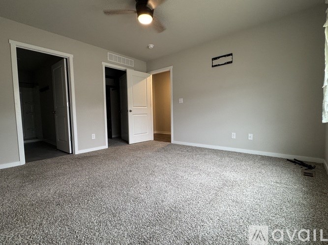 A room with a carpeted floor and a ceiling fan.