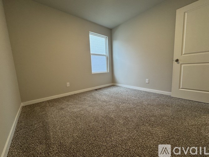 A room with a carpeted floor and a window with blinds.