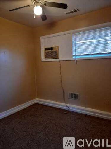 A room with a ceiling fan and a window with blinds.