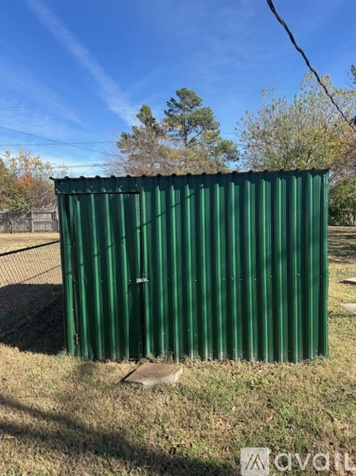 A green metal shed sits in a grassy field.