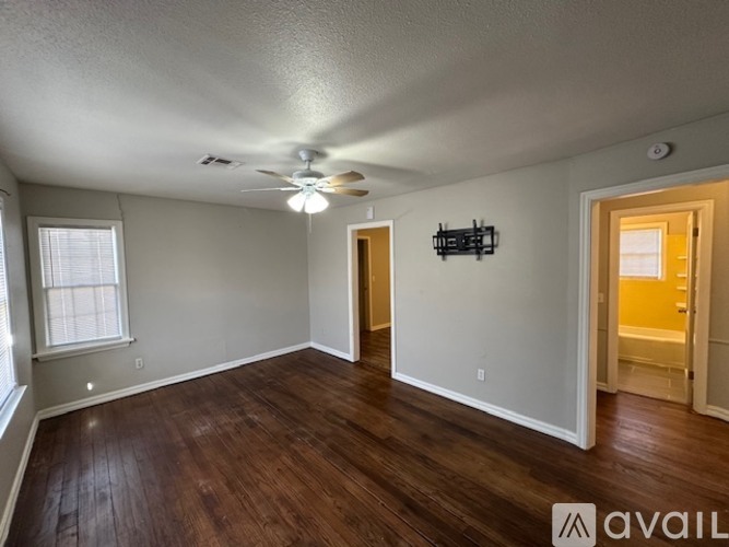 A room with a ceiling fan and wooden floors.